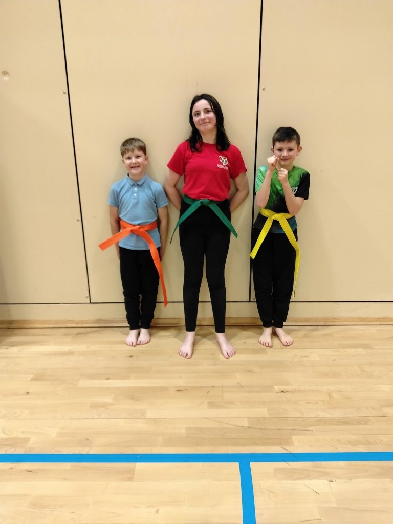 Children's martial arts Redcar class: kids with colored belts pose barefoot.